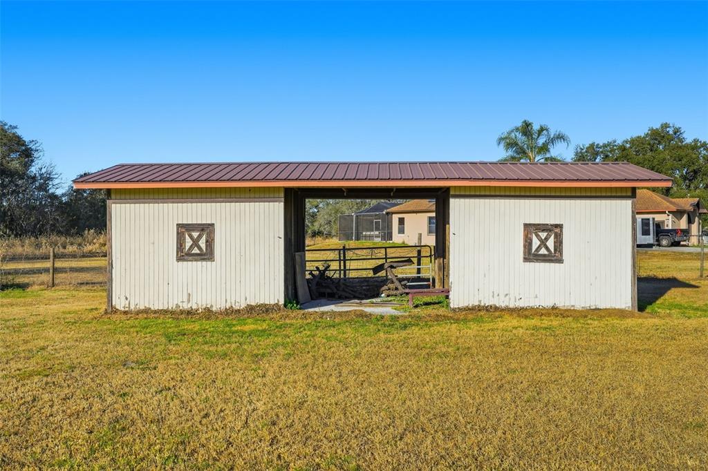 A white, single-story barn with a metal roof and a central open-air stall — 7005 CRIPPLE CREEK ROAD, PLANT CITY, FL