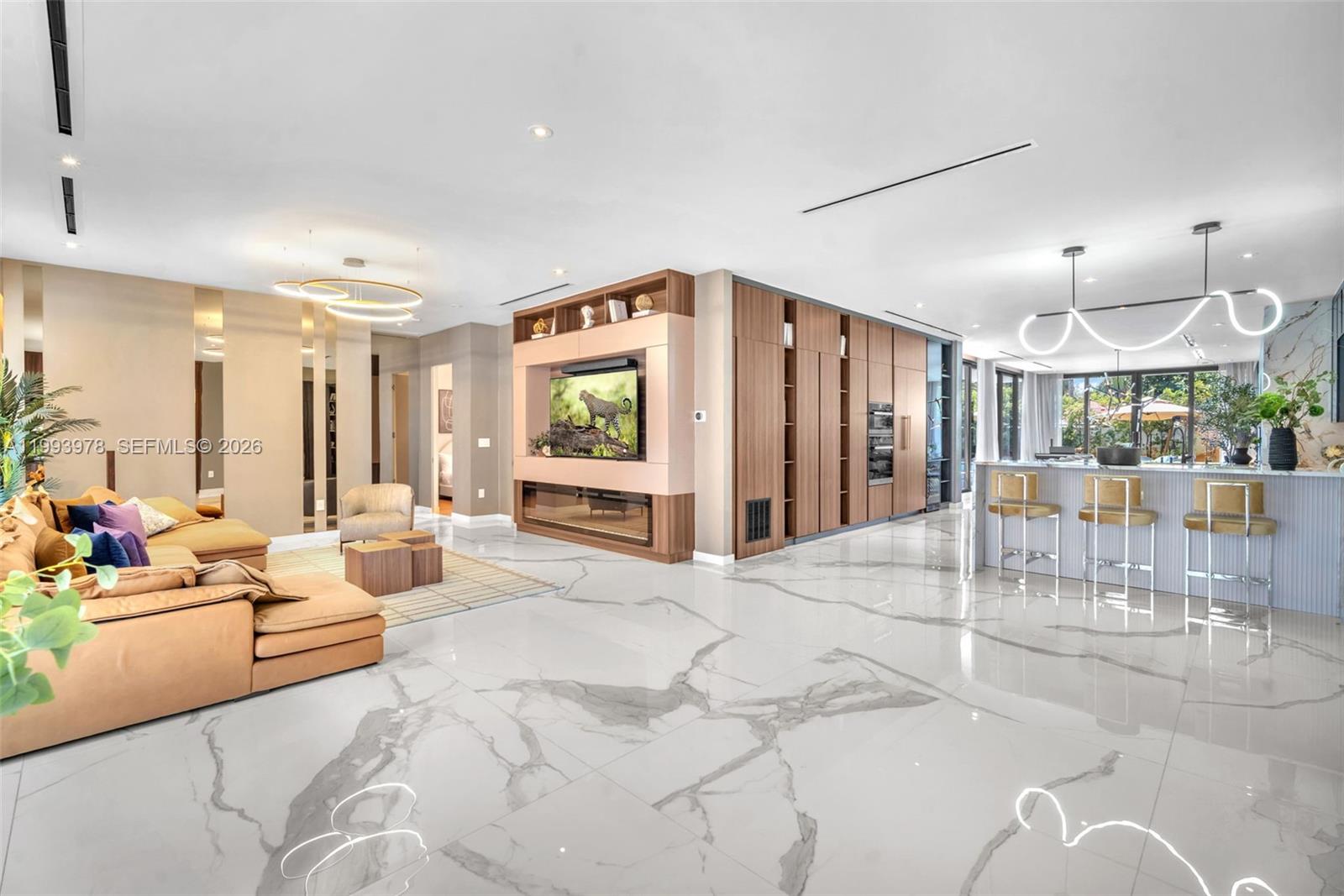 A modern open-concept living room features marble floors, a built-in media wall, and a kitchen island — 46 NE 162nd St, Miami FL 33162, MIAMI, FL