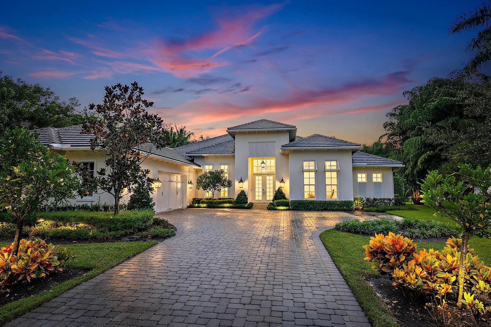A single-story house with a paved driveway and landscaped yard at sunset — 6081 Wildcat Run, West Palm Beach FL 33412, WEST PALM BEACH, FL