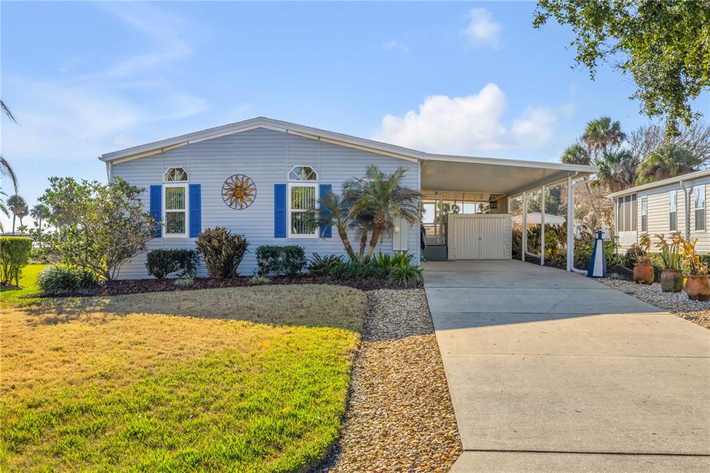 A light blue manufactured home features a concrete driveway, a carport, and blue shutters — 290 NAVAJO DRIVE, OAK HILL, FL