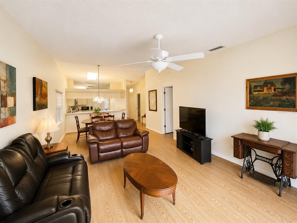 A living room with light wood flooring, a brown leather sofa, and a dining area — 5530 37TH STREET E, BRADENTON, FL