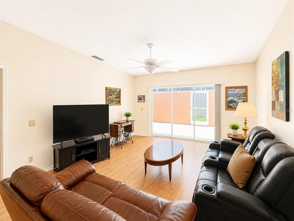 A living room features a black leather sofa, a brown leather loveseat, and wood flooring — 5530 37TH STREET E, BRADENTON, FL