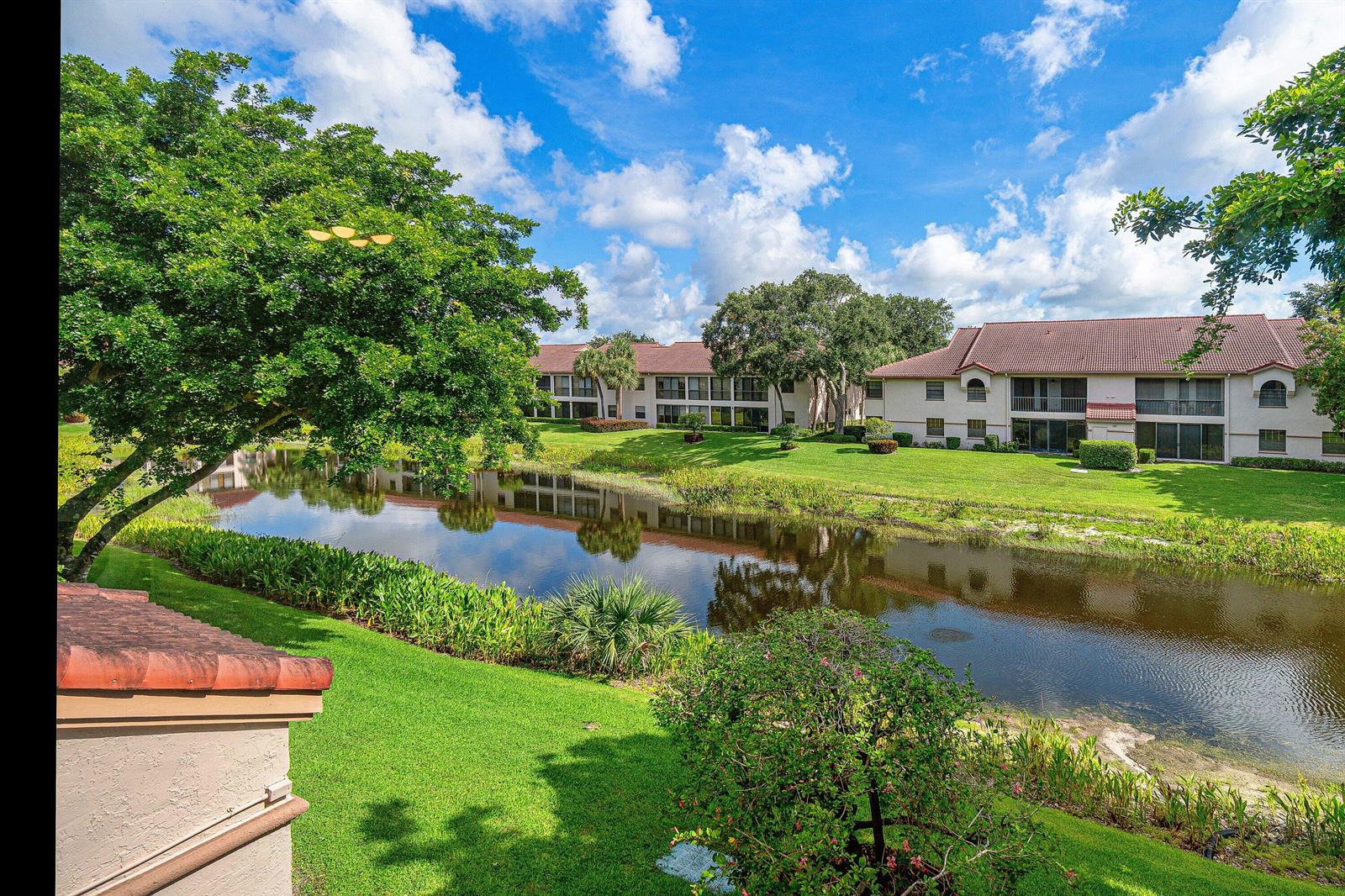 A view of a pond surrounded by green lawns and multi-story apartment buildings — 5171 Europa Drive # G, Boynton Beach FL 33437, BOYNTON BEACH, FL