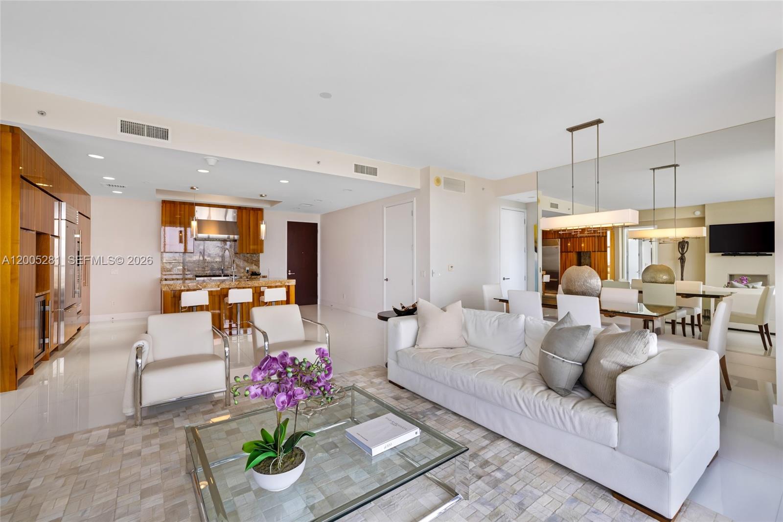 An open-concept living and dining area features white tile floors, modern furniture, and wood cabinetry — 9701 Collins Ave # 805S, Bal Harbour FL 33154, BAL HARBOUR, FL