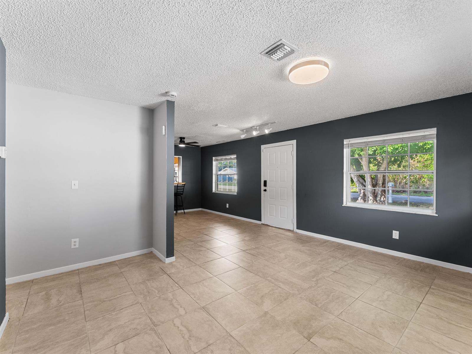 An empty room with light-colored tile flooring, gray walls, and a white front door — 304 8th Avenue SW, Vero Beach FL 32962, VERO BEACH, FL