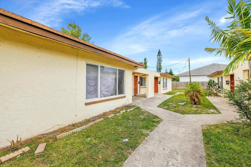 An exterior view of a single-story apartment building with a concrete walkway and lawn — LAUDERHILL, FL
