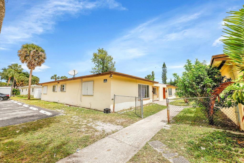 A single-story yellow house with a flat roof, chain-link fence, and a concrete walkway — LAUDERHILL, FL