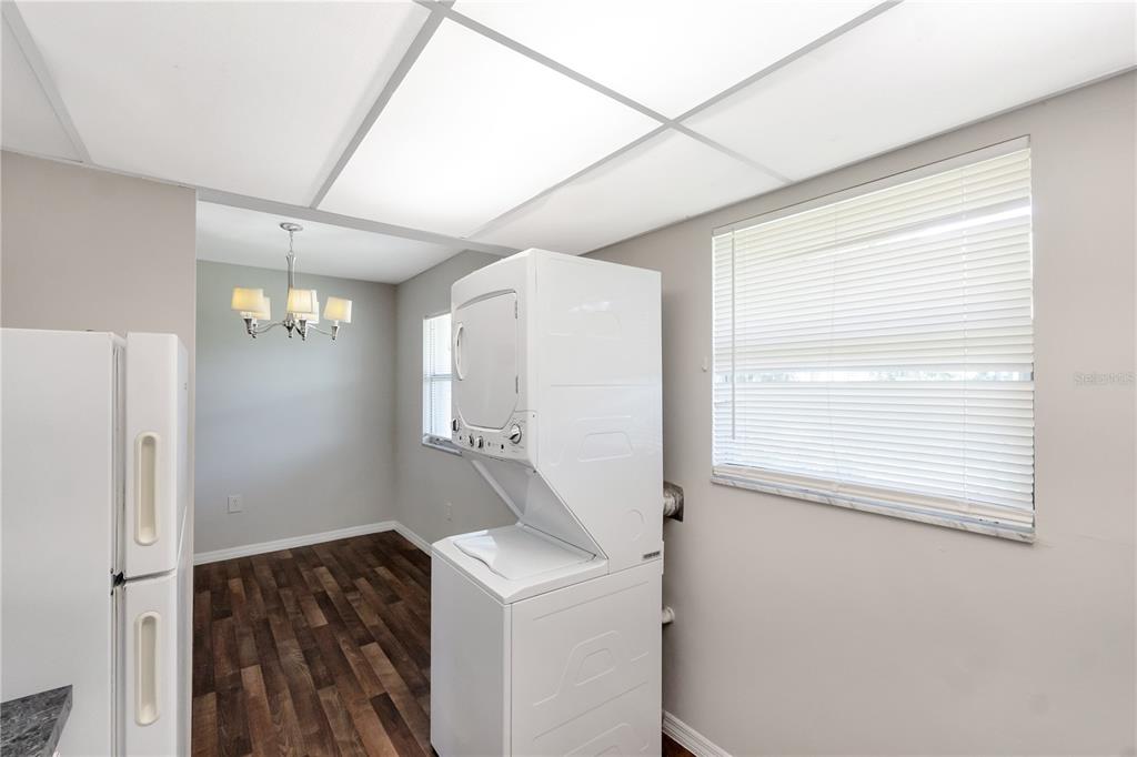 A laundry area with a stacked washer and dryer sits next to a dining space — 201 KINGS BOULEVARD UNIT 5, SUN CITY CENTER, FL