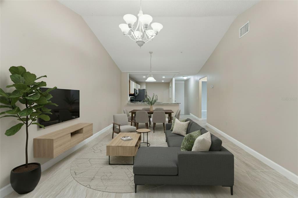 A living room with a gray sectional, wood media console, dining area, and vaulted ceilings — 683 POST OAK CIRCLE UNIT 105, ALTAMONTE SPRINGS, FL
