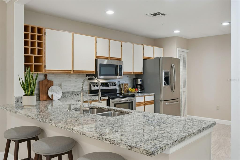 A kitchen features granite countertops, stainless steel appliances, white cabinets, and a breakfast bar — 683 POST OAK CIRCLE UNIT 105, ALTAMONTE SPRINGS, FL