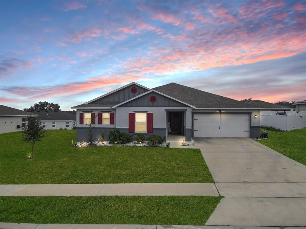 A single-story suburban house with a gray exterior, red shutters, and a two-car garage — 2220 GLADIOLUS LANE, MASCOTTE, FL