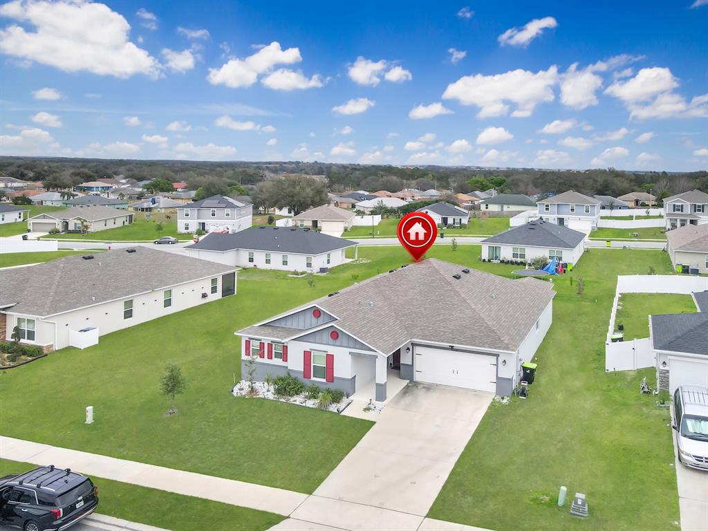 An aerial view shows a single-story suburban house with a gray roof and attached garage — 2220 GLADIOLUS LANE, MASCOTTE, FL