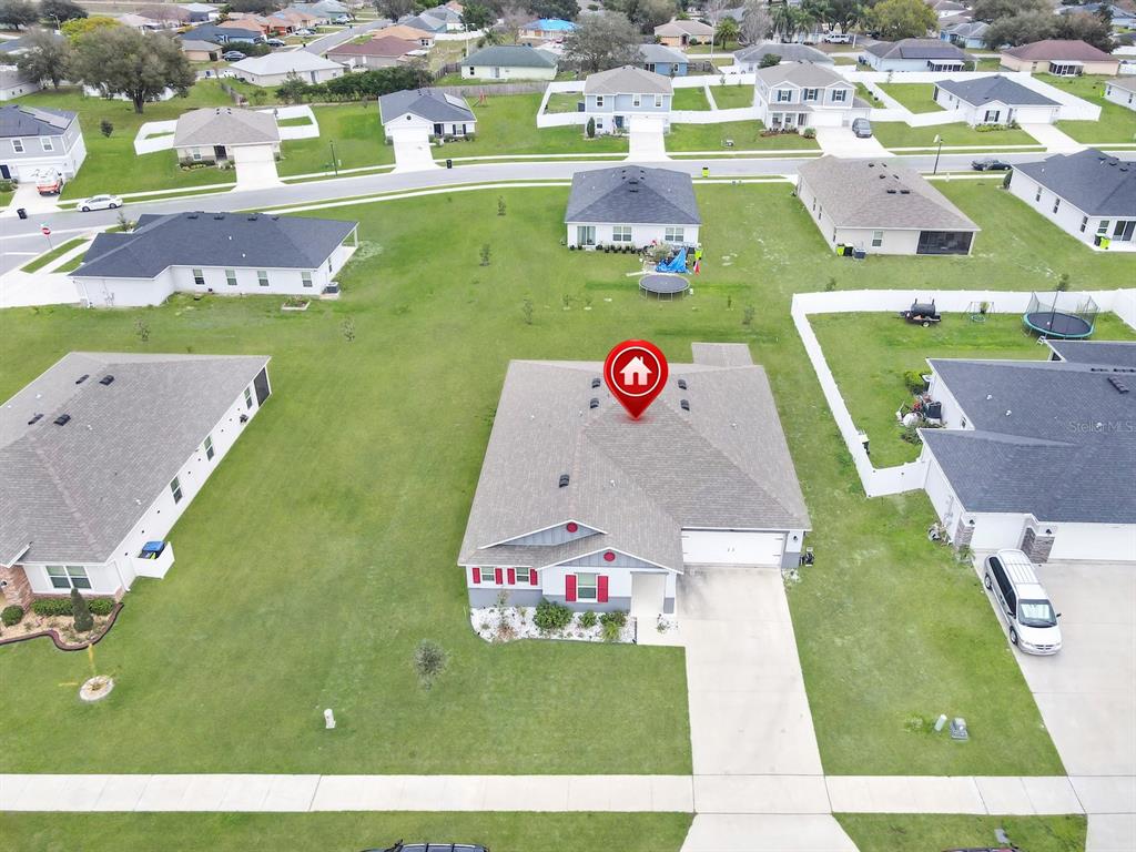 An aerial view shows a suburban house with a red-shuttered facade and a large lawn — 2220 GLADIOLUS LANE, MASCOTTE, FL