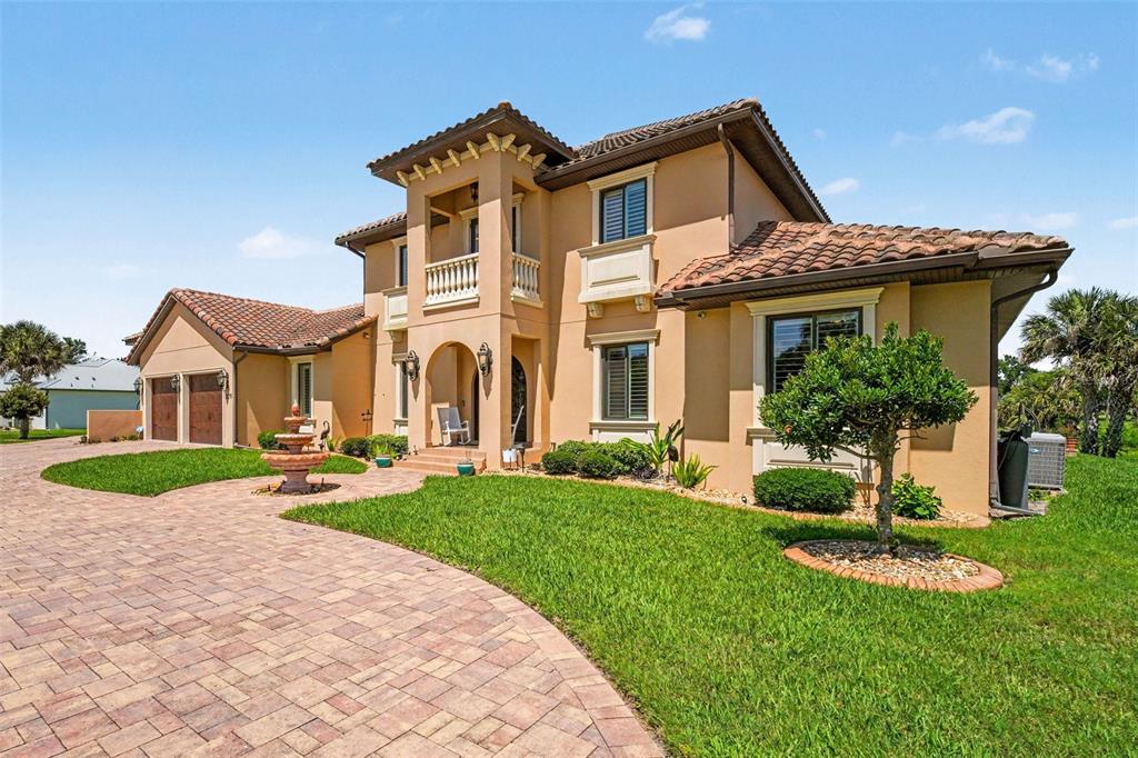 A large two-story house with a tile roof and attached garage sits behind a pond — 2179 ARNOLD PALMER DRIVE, TITUSVILLE, FL