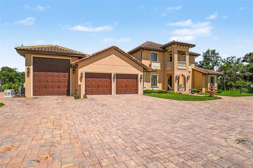 A two-story stucco house with a tile roof and a paved circular driveway — 2179 ARNOLD PALMER DRIVE, TITUSVILLE, FL