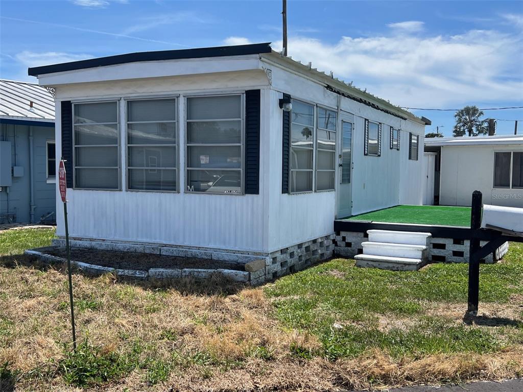A white mobile home with a screened-in front porch and a small green deck — 12674 SEMINOLE BOULEVARD UNIT M1, LARGO, FL