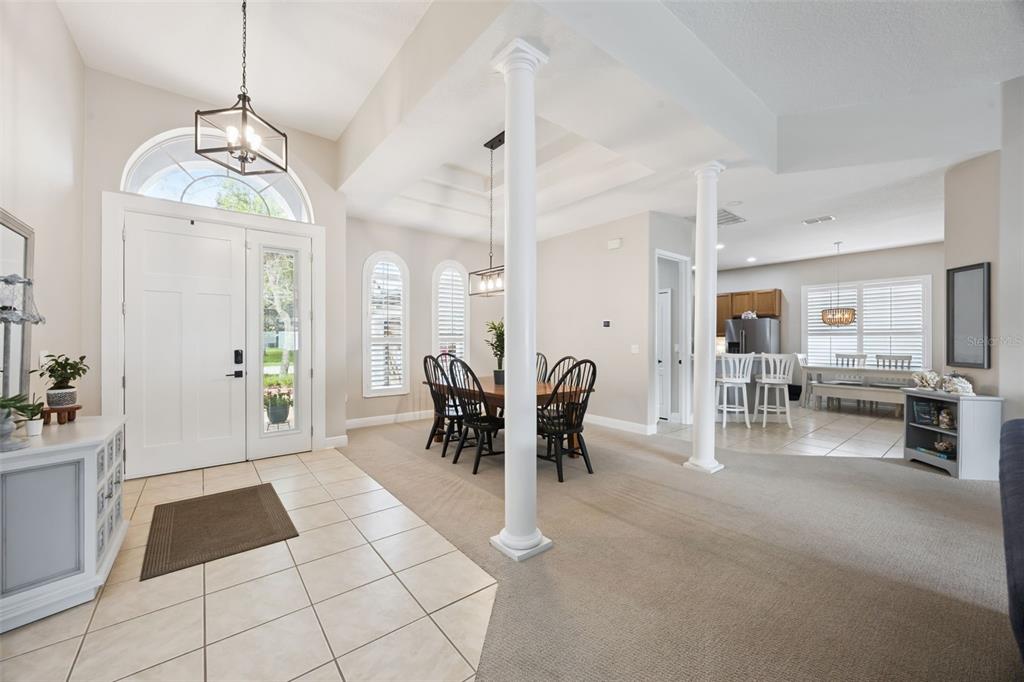 An open-concept dining area and entryway feature tile and carpet flooring with two white columns — 3121 JUNEBERRY TERRACE, OVIEDO, FL
