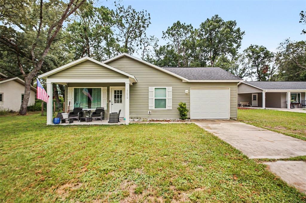 A single-story house with light green siding, a front porch, and an attached garage — 17050 SE 60TH STREET, OCKLAWAHA, FL