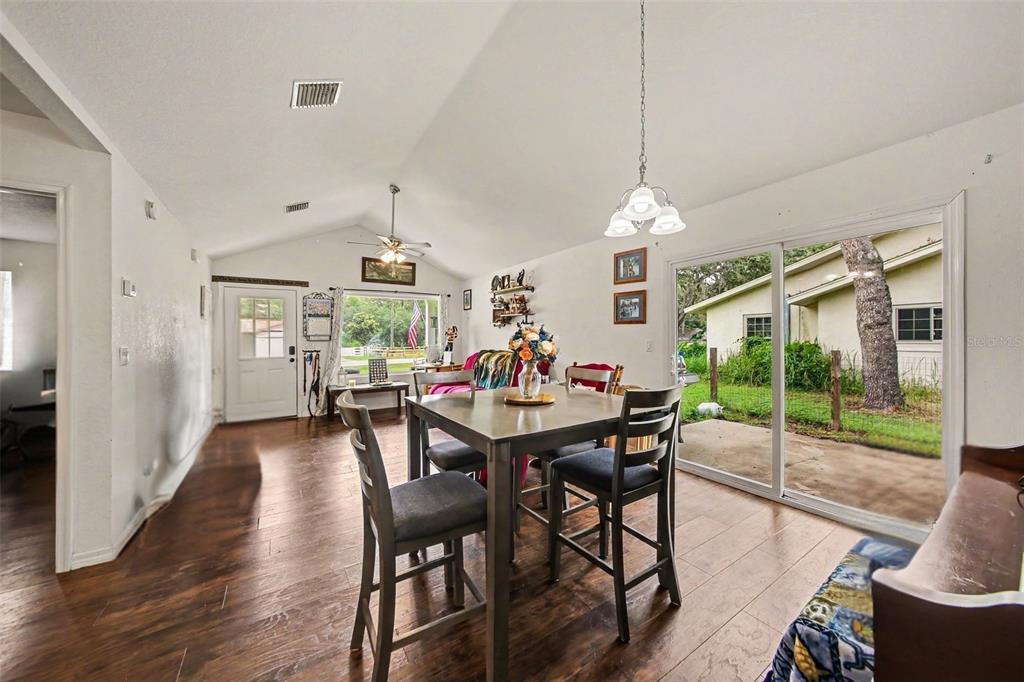 A dining area with wood-look floors, a vaulted ceiling, and sliding glass doors to outside — 17050 SE 60TH STREET, OCKLAWAHA, FL