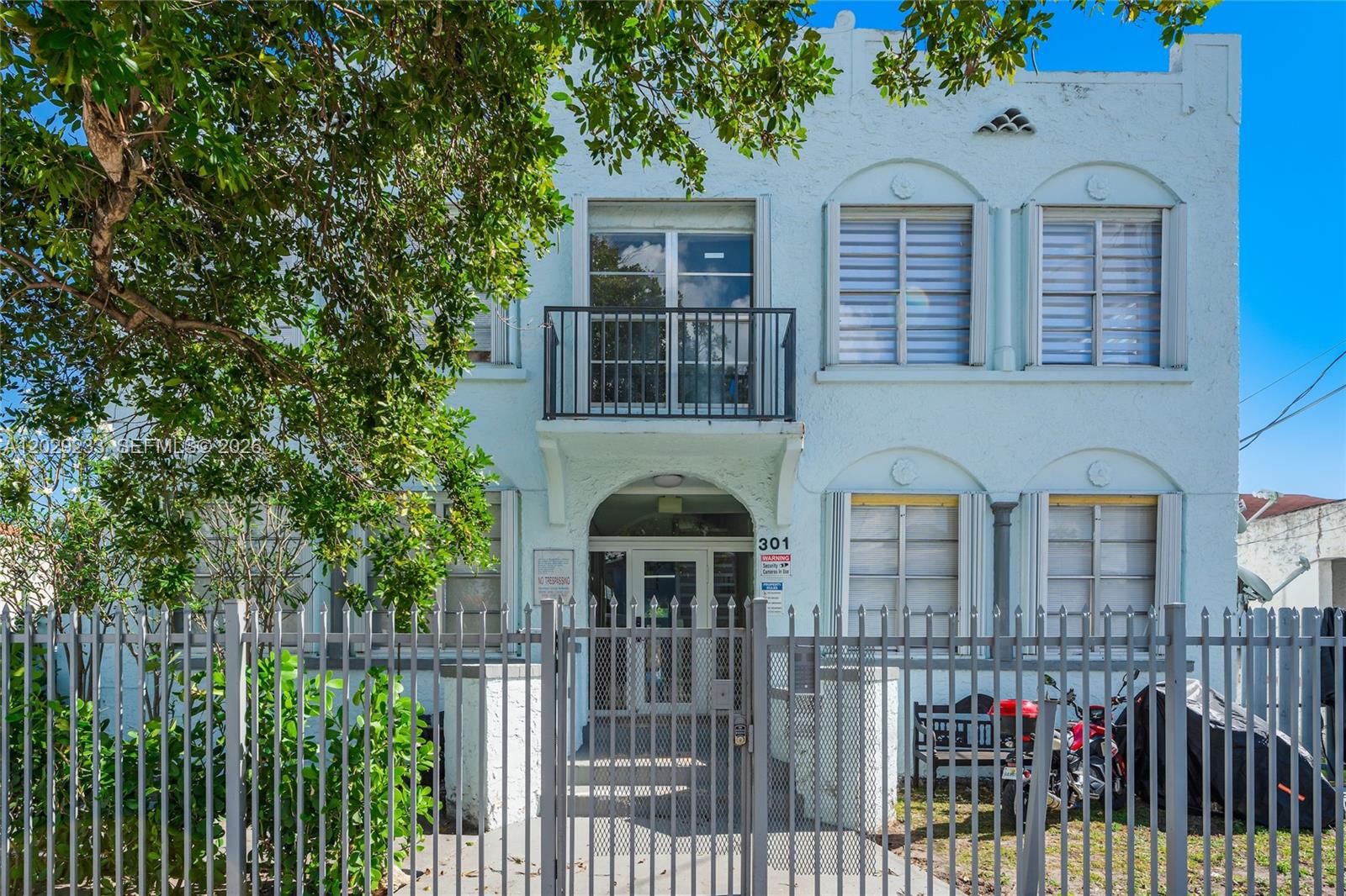A two-story light blue building with a gated entrance, balcony, and arched window frames — 301 SW 10th Ave # 7, Miami FL 33130, MIAMI, FL
