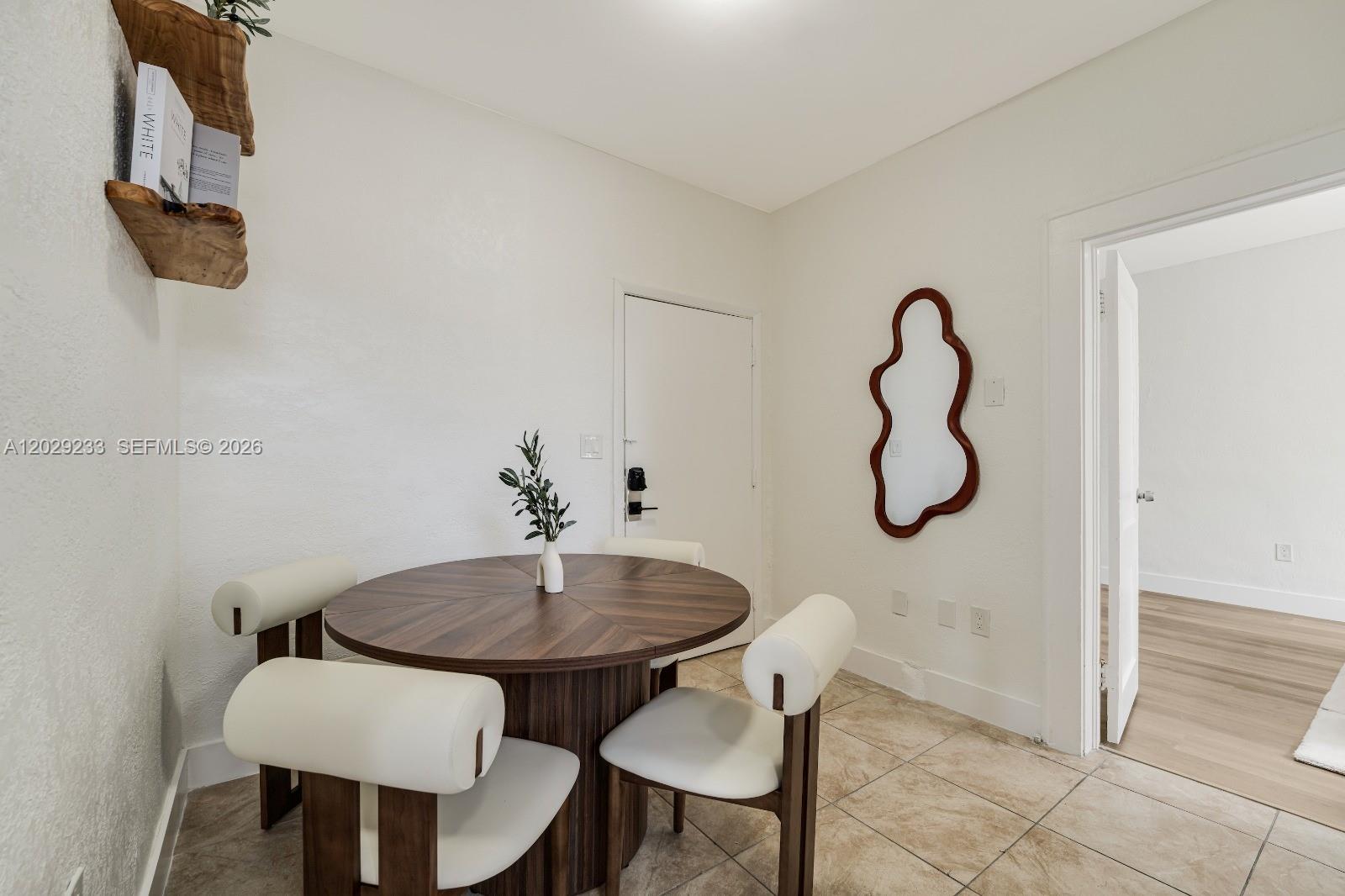 A dining area features a round wooden table, four white chairs, and a wall mirror — 301 SW 10th Ave # 7, Miami FL 33130, MIAMI, FL
