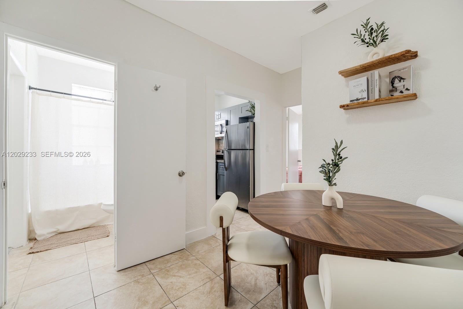 A dining area features a round wooden table, white chairs, and shelves on a white wall — 301 SW 10th Ave # 7, Miami FL 33130, MIAMI, FL