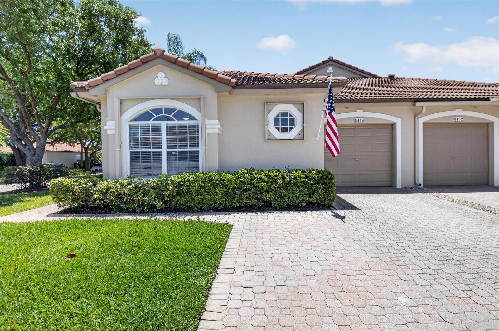 A tan single-story house with a tiled roof, a paved driveway, and a small front lawn — 8446 Vía Serena, Boca Raton FL 33433, BOCA RATON, FL