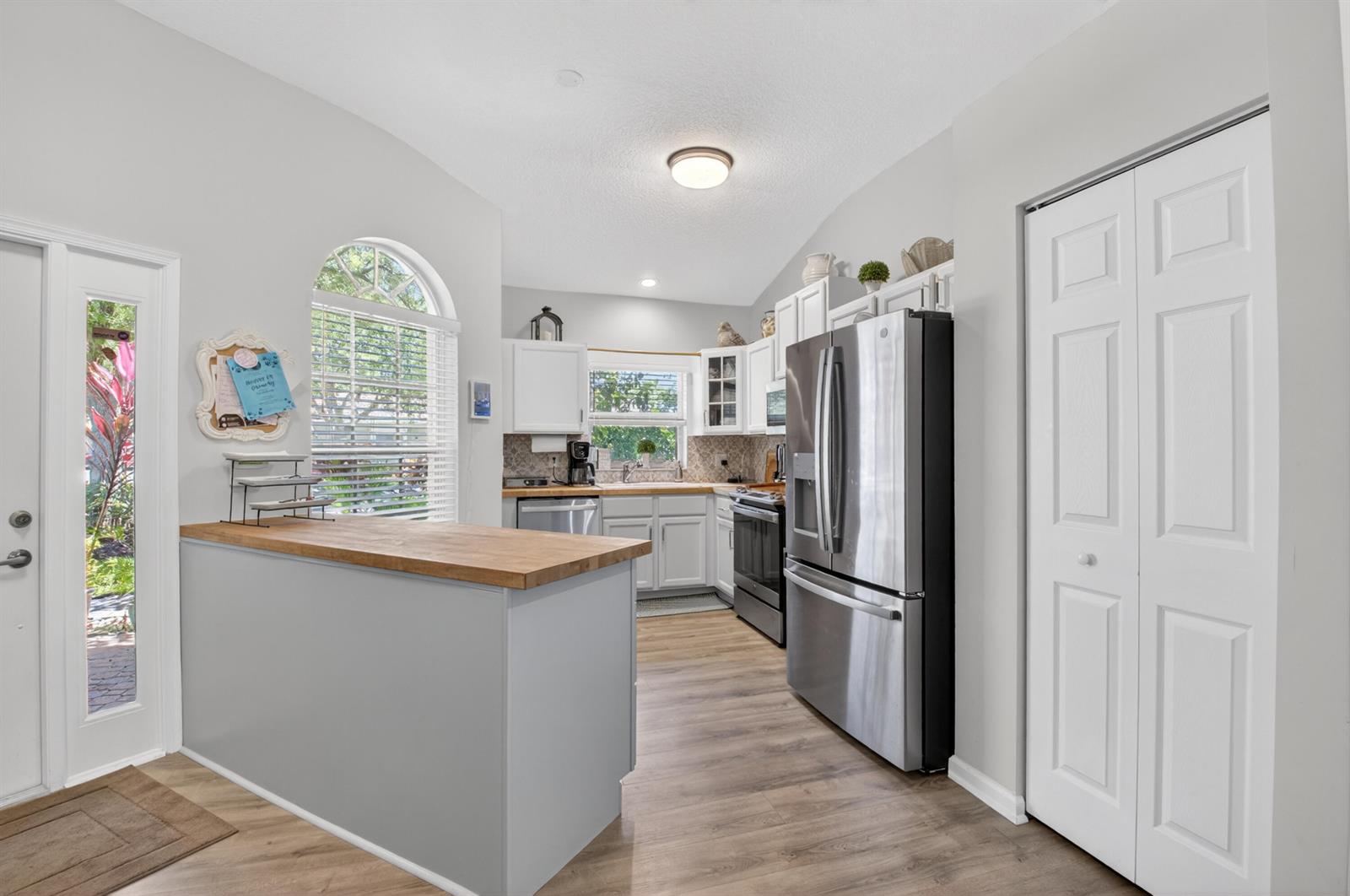 A kitchen features white cabinets, stainless steel appliances, a wood countertop, and light flooring — 8446 Vía Serena, Boca Raton FL 33433, BOCA RATON, FL