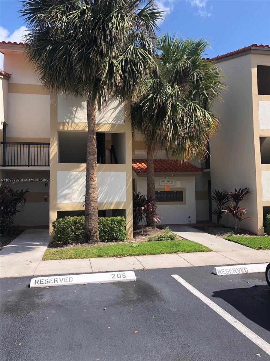 The exterior of a multi-story apartment building features palm trees and reserved parking spaces — 9861 Nob Hill Ct # 9861, Sunrise FL 33351, SUNRISE, FL