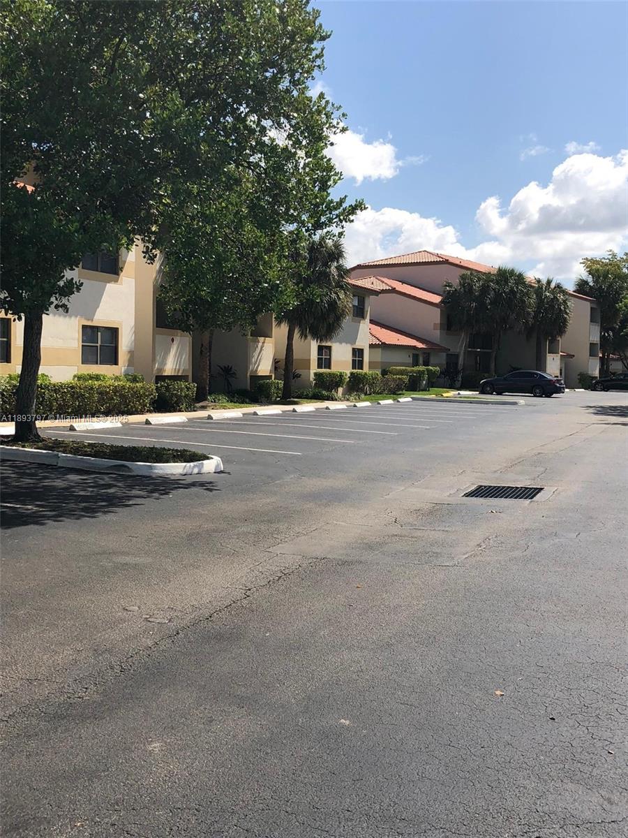 An exterior view of a multi-story apartment building with a parking lot in front — 9861 Nob Hill Ct # 9861, Sunrise FL 33351, SUNRISE, FL