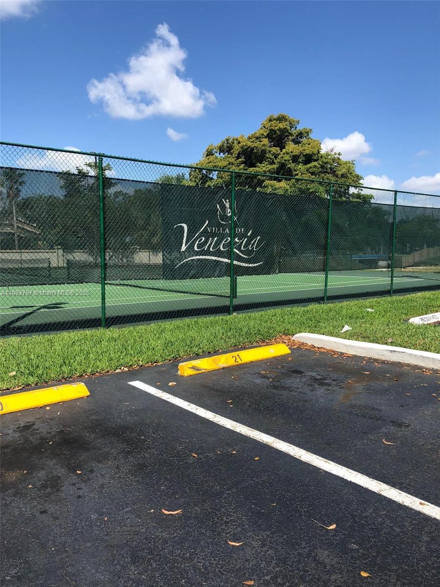 A tennis court is enclosed by a green chain-link fence with a branded windscreen — 9861 Nob Hill Ct # 9861, Sunrise FL 33351, SUNRISE, FL