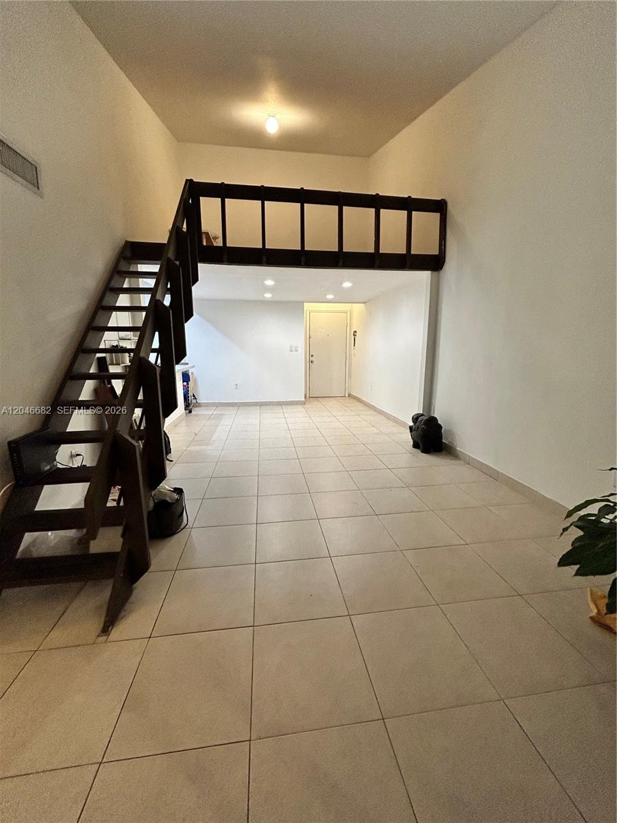 An interior view shows a tiled living area with a loft and a wooden staircase — 9421 Fontainebleau Blvd # 35, Miami FL 33172, MIAMI, FL