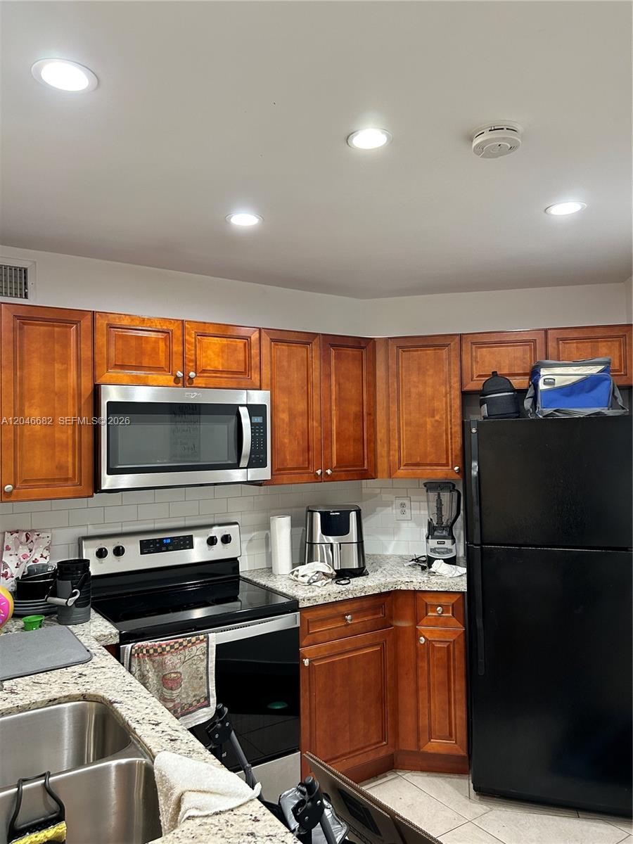 A kitchen features wood cabinets, granite countertops, stainless steel appliances, and a black refrigerator — 9421 Fontainebleau Blvd # 35, Miami FL 33172, MIAMI, FL