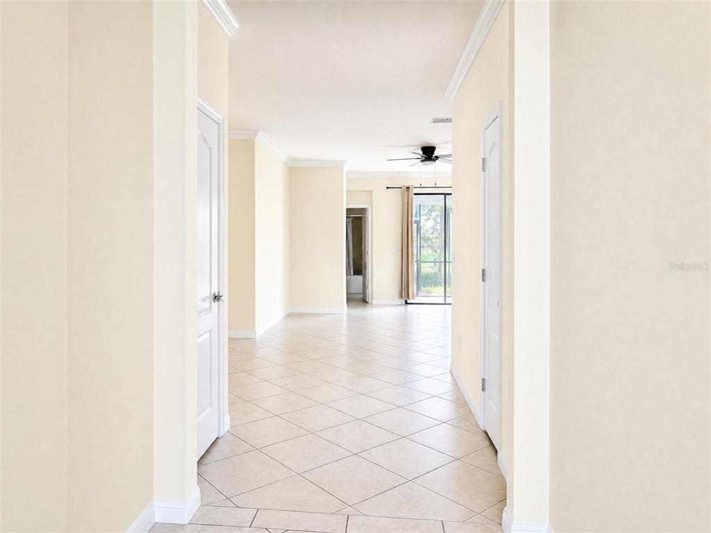 A tiled hallway leads to an open living area with a ceiling fan and sliding doors — 12889 RICHEZZA DRIVE, VENICE, FL