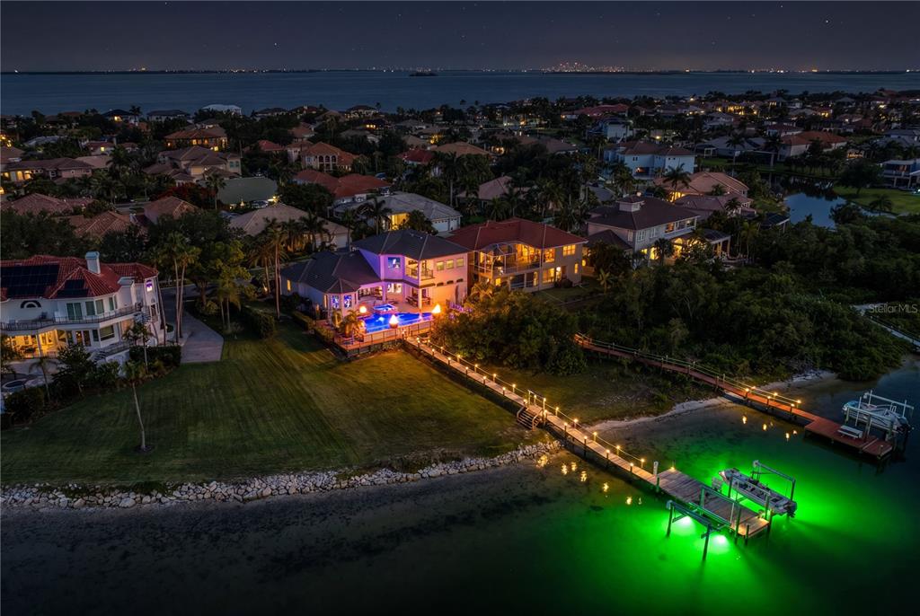 An aerial night view of a waterfront house with a pool and illuminated boat dock — 1317 JUMANA LOOP, APOLLO BEACH, FL