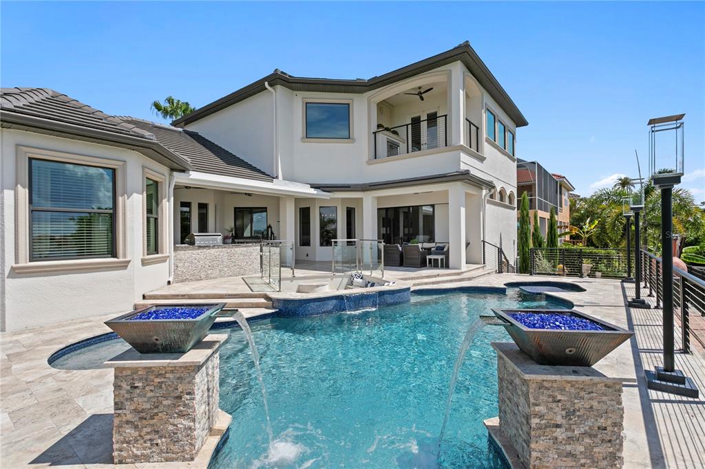 A two-story house exterior features a swimming pool with two stone fountains and a patio — 1317 JUMANA LOOP, APOLLO BEACH, FL
