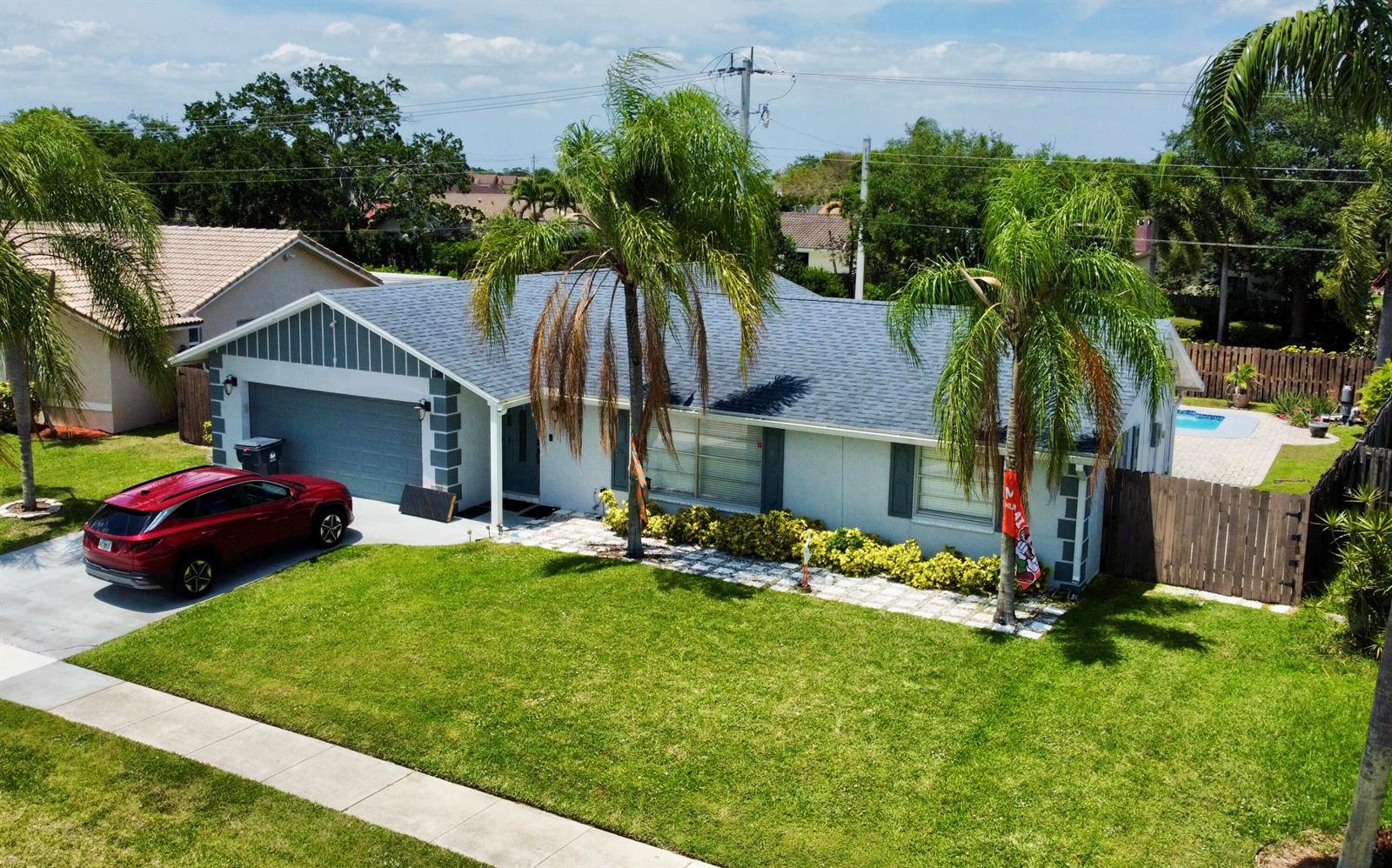 A single-story house with a gray garage, blue roof, and palm trees on a lawn — 1381 Wyndcliff, Wellington FL 33414, WELLINGTON, FL