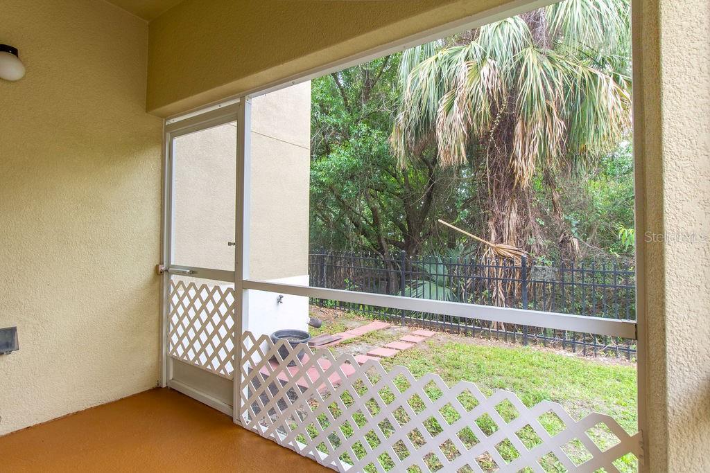 A screened-in patio with a concrete floor overlooks a grassy yard and trees — 6445 CYPRESSDALE DRIVE UNIT 102, RIVERVIEW, FL