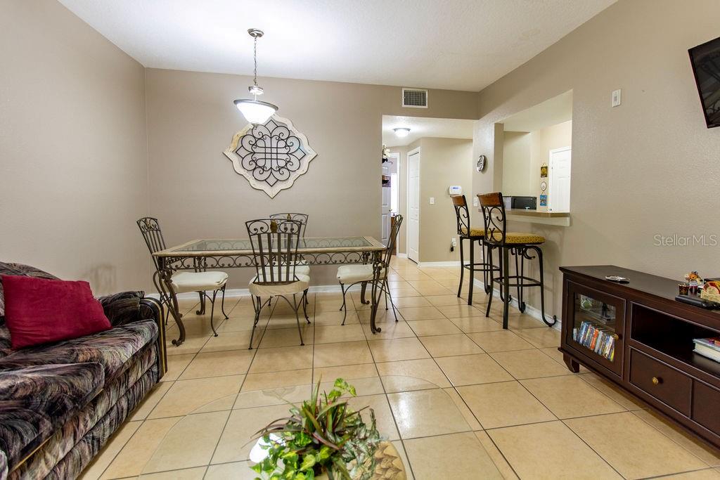 A dining area with a glass-top table, metal chairs, and a breakfast bar with stools — 6445 CYPRESSDALE DRIVE UNIT 102, RIVERVIEW, FL