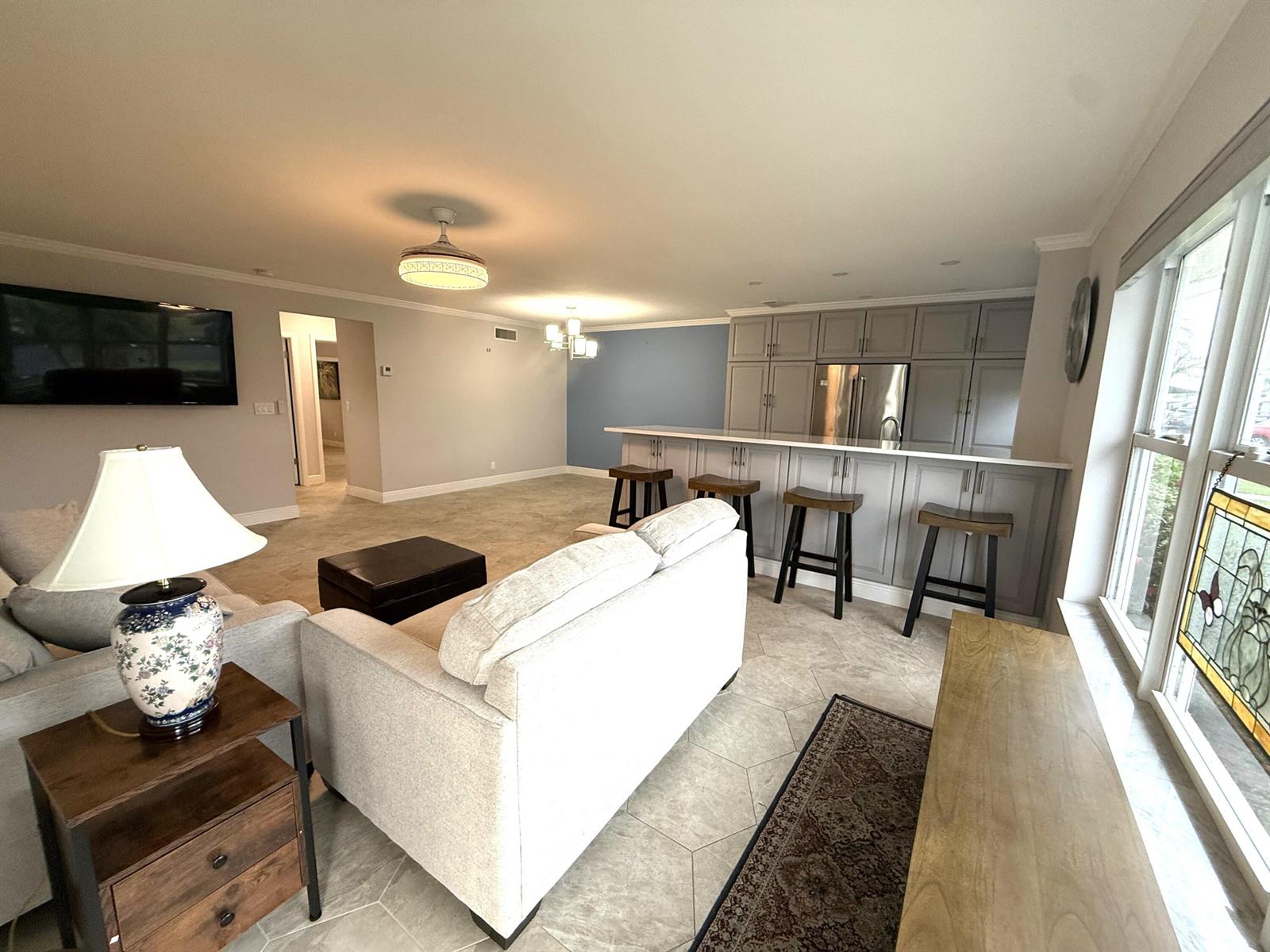 A living room and kitchen area feature gray cabinetry, a breakfast bar, and tile flooring — 916 Savannas Point Drive # B, Fort Pierce FL 34982, FORT PIERCE, FL