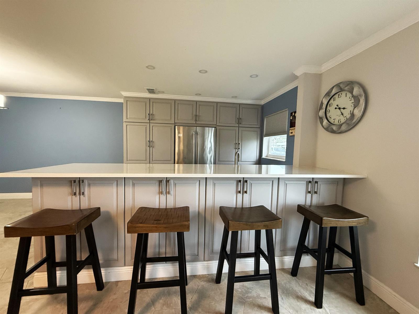An open-concept living room features a kitchen with gray cabinets, bar seating, and tile flooring — 916 Savannas Point Drive # B, Fort Pierce FL 34982, FORT PIERCE, FL