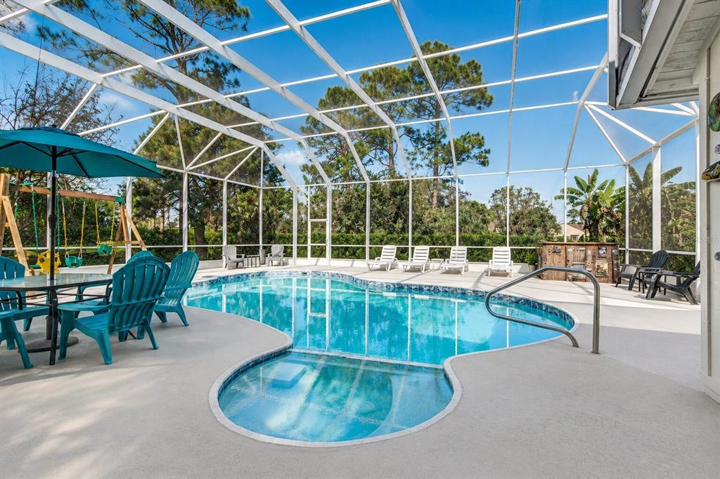 A screened-in patio features a swimming pool with an attached spa and outdoor furniture — 932 PELICAN BAY DRIVE, DAYTONA BEACH, FL