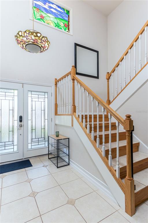 An entryway features a tiled floor, a wooden staircase, and a stained-glass light fixture — 932 PELICAN BAY DRIVE, DAYTONA BEACH, FL