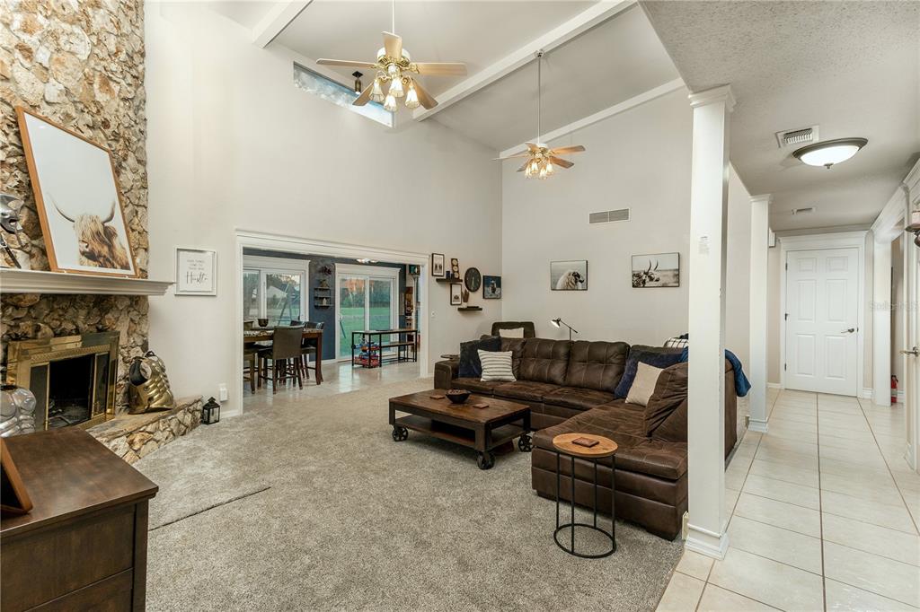 A living room features a stone fireplace, vaulted ceilings, and a brown sectional sofa — 932 PELICAN BAY DRIVE, DAYTONA BEACH, FL