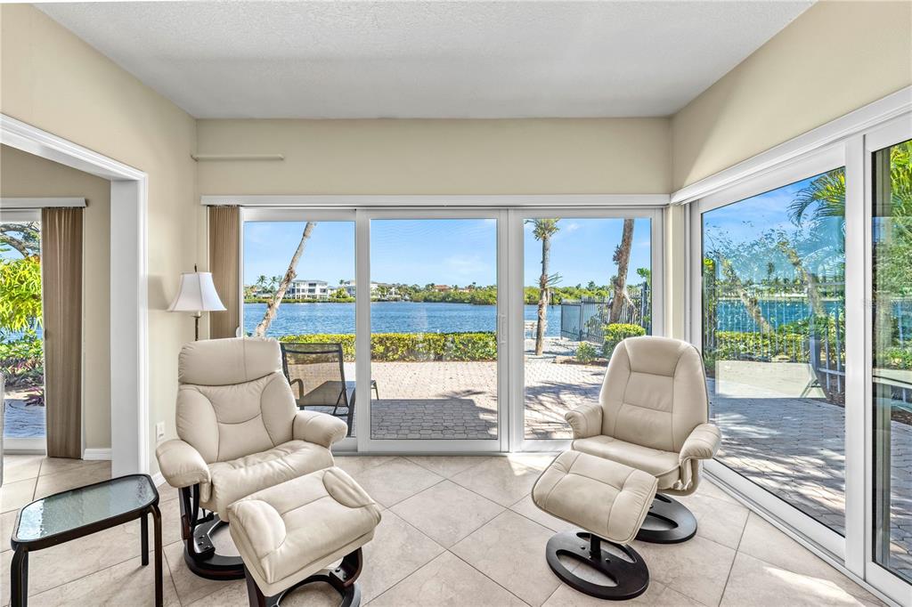 A sunroom with tile floors and two recliners overlooks a waterfront patio and canal — 1320 MOONMIST DRIVE UNIT B-11, SARASOTA, FL