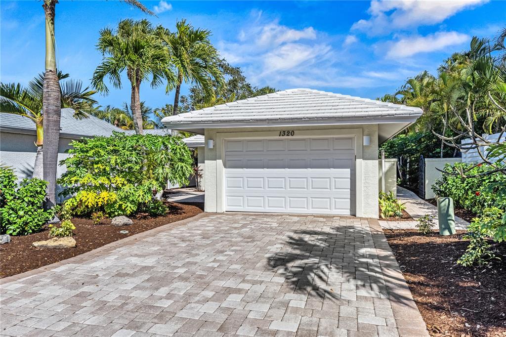 A paved driveway leads to a single-car garage with a white door and tiled roof — 1320 MOONMIST DRIVE UNIT B-11, SARASOTA, FL