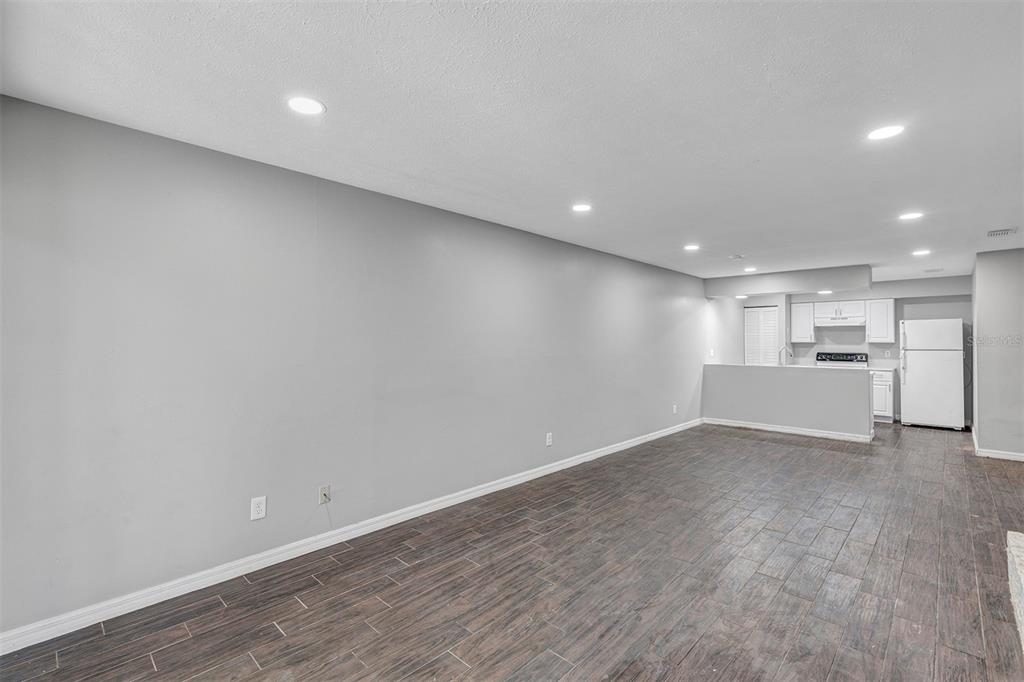 A living room with gray walls, dark wood-look tile flooring, and an open kitchen — 3990 SE 17TH CT UNIT B, OCALA, FL
