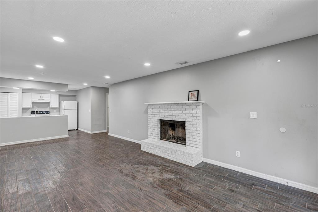 A living room features a white brick fireplace, gray walls, and dark wood-look tile flooring — 3990 SE 17TH CT UNIT B, OCALA, FL