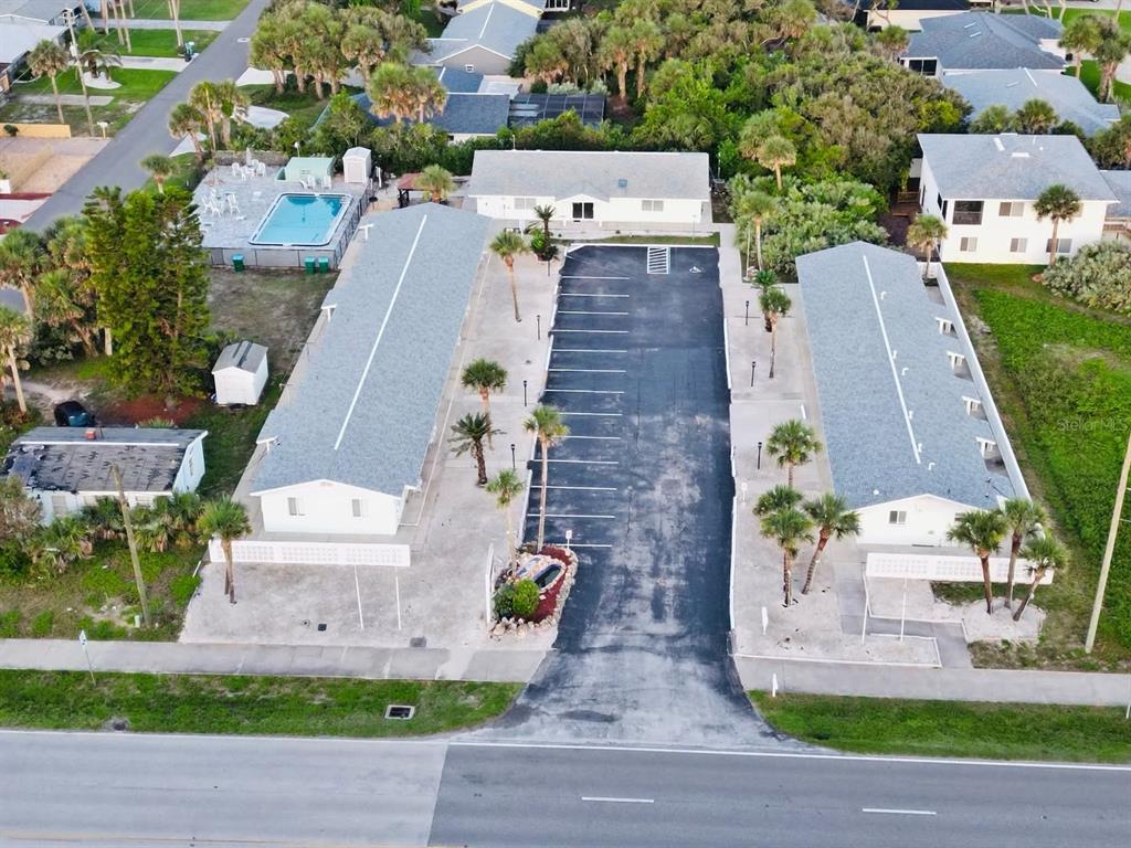 An aerial view shows two long buildings flanking a central parking lot with palm trees — 1708 S ATLANTIC AVENUE, NEW SMYRNA BEACH, FL