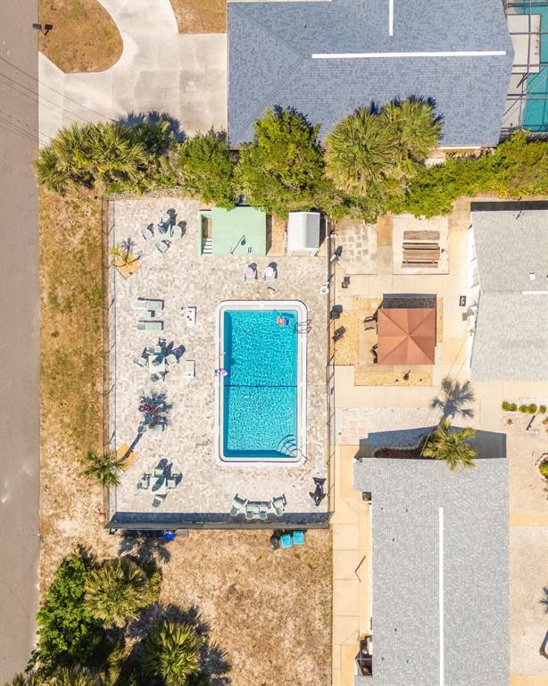 An aerial view shows a rectangular swimming pool surrounded by a paved patio and lounge chairs — 1708 S ATLANTIC AVENUE, NEW SMYRNA BEACH, FL